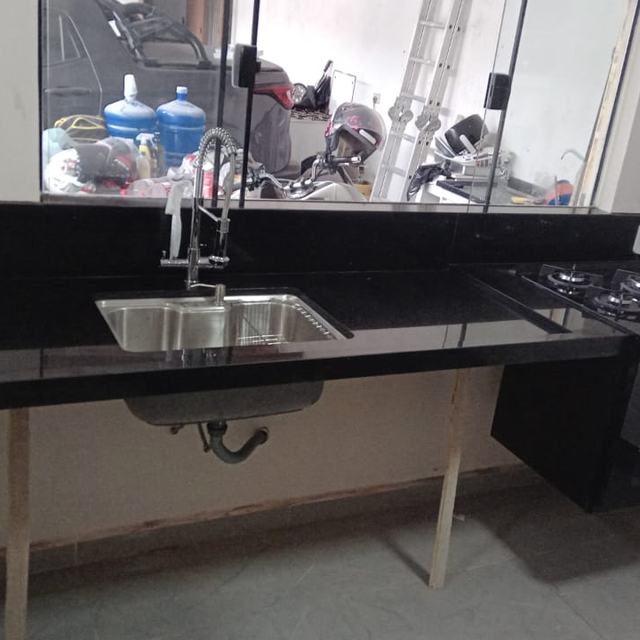 Bancada de cozinha em granito preto com cuba de inox e cooktop
